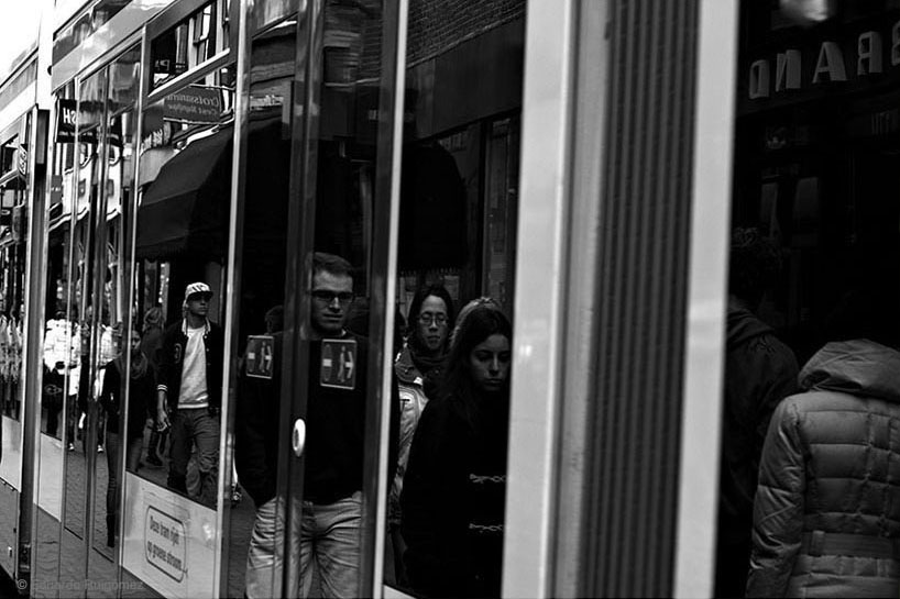 Paseantes reflejados en los cristales de un tranvía en marcha.