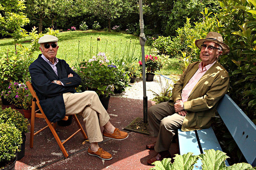Dos personas sonrientes negocian en un jardín.